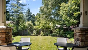 An outdoor patio with two tables and chairs, surrounded by a well-maintained lawn and various trees. - Impeccable Décor and Furnishing, Splendid Neighborhood, Pet Friendly, Fenced Backyard, Next to Park (Portland)