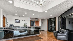 A hotel lobby with a reception desk, a conference room, and a leather sofa.
