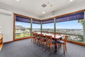 A conference room with a large table and chairs, large windows with blinds, and a view of a residential area. - Comfort Inn The Lakes (Mount Gambier)