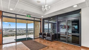 A hotel lobby with a reception desk, seating area, and a view of the cityscape.
