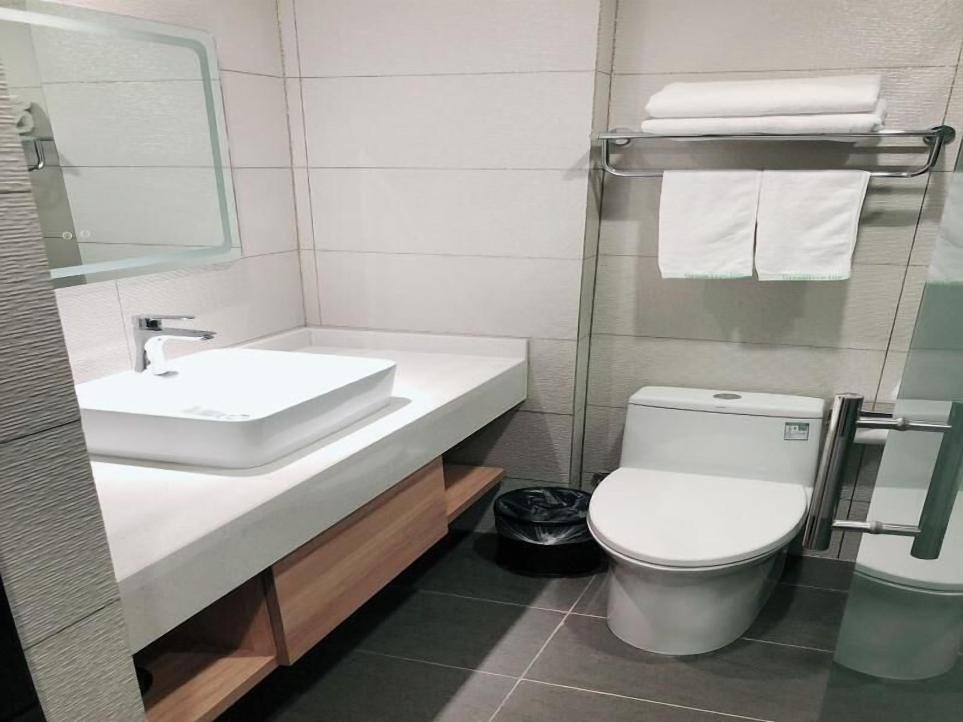 A modern bathroom with a white sink, mirror, and toilet.
