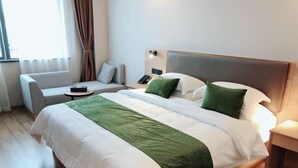 Une chambre d’hôtel avec un grand lit, un canapé, une table de chevet et une fenêtre avec des rideaux.