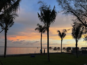 A beach scene with palm trees, a pier, and overwater bungalows. - Ban Mai Beach Villa Phu Quoc (Phu Quoc)