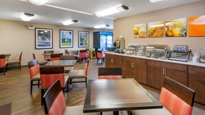 Un restaurante con cabinas y mesas, una barra con electrodomésticos y cuadros en la pared.