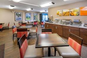 Un restaurant avec des banquettes et des tables, un comptoir avec des appareils électroménagers et des tableaux encadrés au mur.