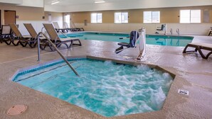 Una piscina interior con sillas de descanso y un jacuzzi.