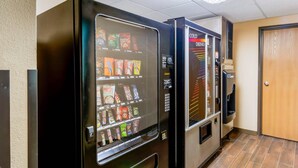 Máquina expendedora con aperitivos y un dispensador de bebidas frías en un pasillo.