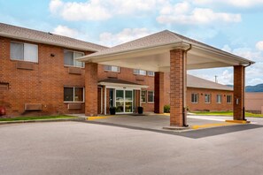 A brick building with a covered entrance, large windows, and a clear sky.