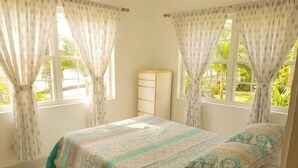 Ein Schlafzimmer mit zwei Betten, einem Nachttisch und einem Fenster mit Vorhängen.