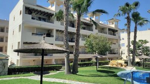 A resort with multiple balconies, a swimming pool, and palm trees. - stunning apartment overlooking the pool (Orihuela)