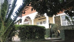 Un edificio con fachada blanca, paredes de ladrillo rojo y un patio cubierto.