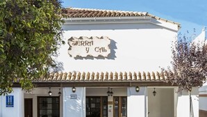 A building with a sign that reads "SIERRA y CAL" and a blue sign with an 'H' indicating a hotel.