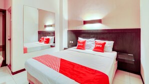 A hotel room with a large bed, a bedside table, a mirror, and a wall-mounted light. - OYO Flagship  90425 Hotel 22 (Surabaya)