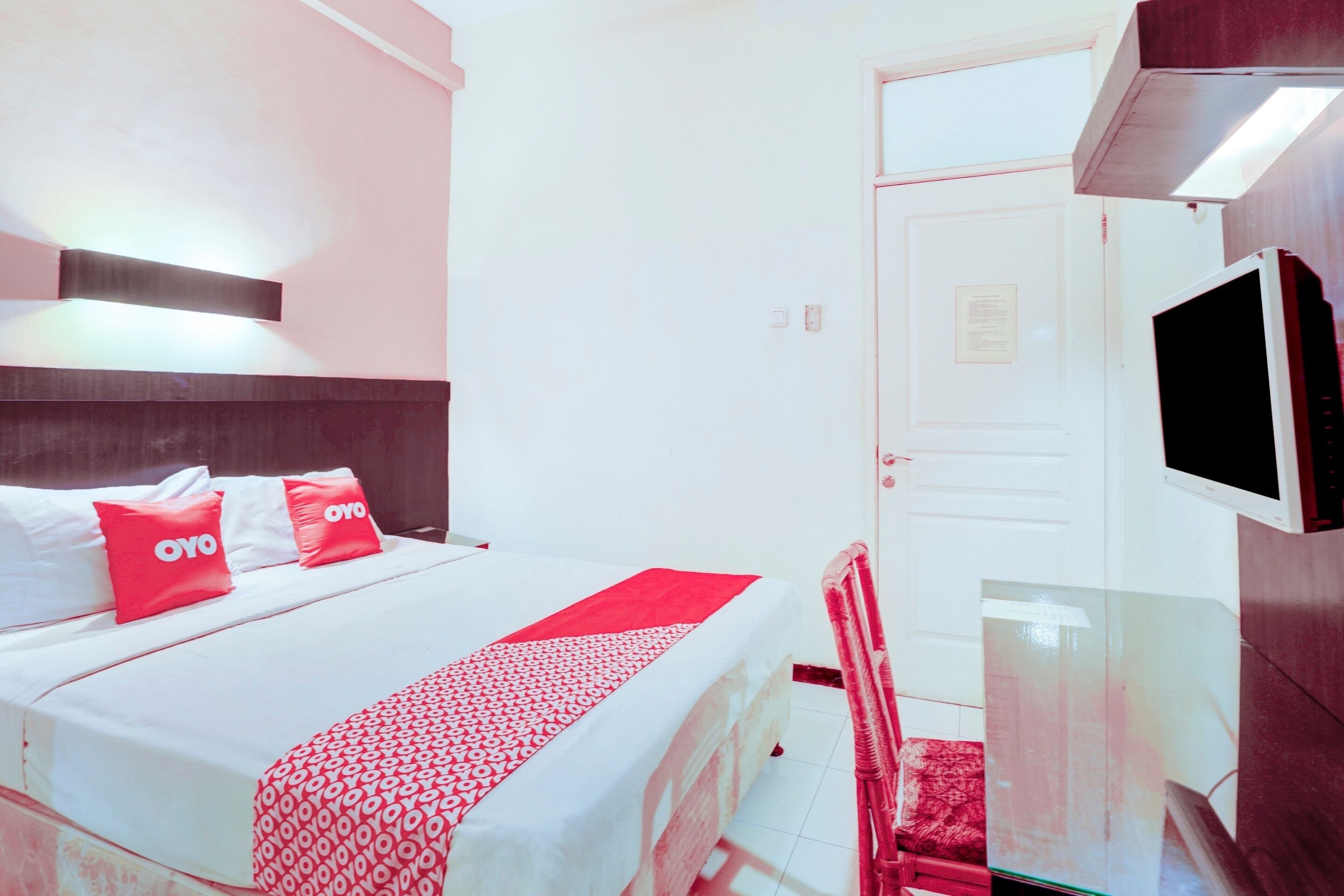 A hotel room with a bed, a TV, a desk, and a chair.