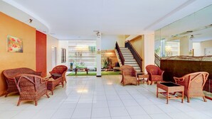 A spacious lobby with wicker furniture, a staircase, and a view of the outdoors. - OYO Flagship  90425 Hotel 22 (Surabaya)