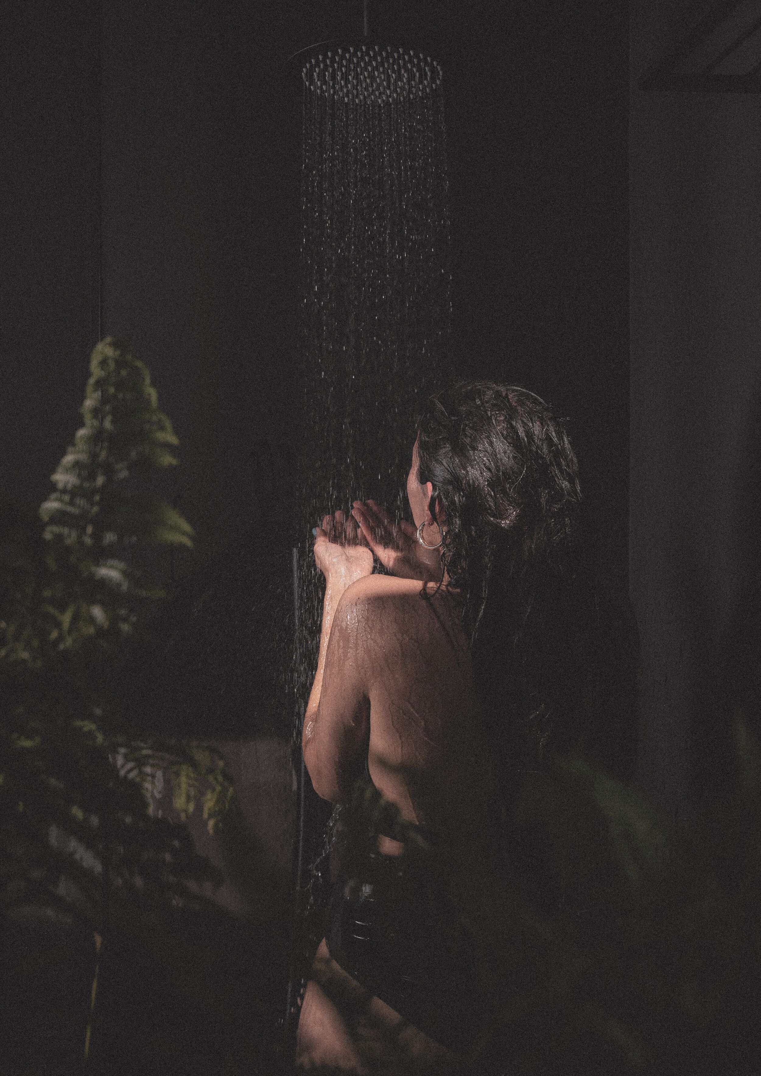 A person in a dimly lit room with a showerhead.