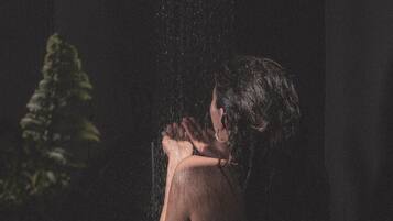 A person in a dimly lit room with a showerhead.