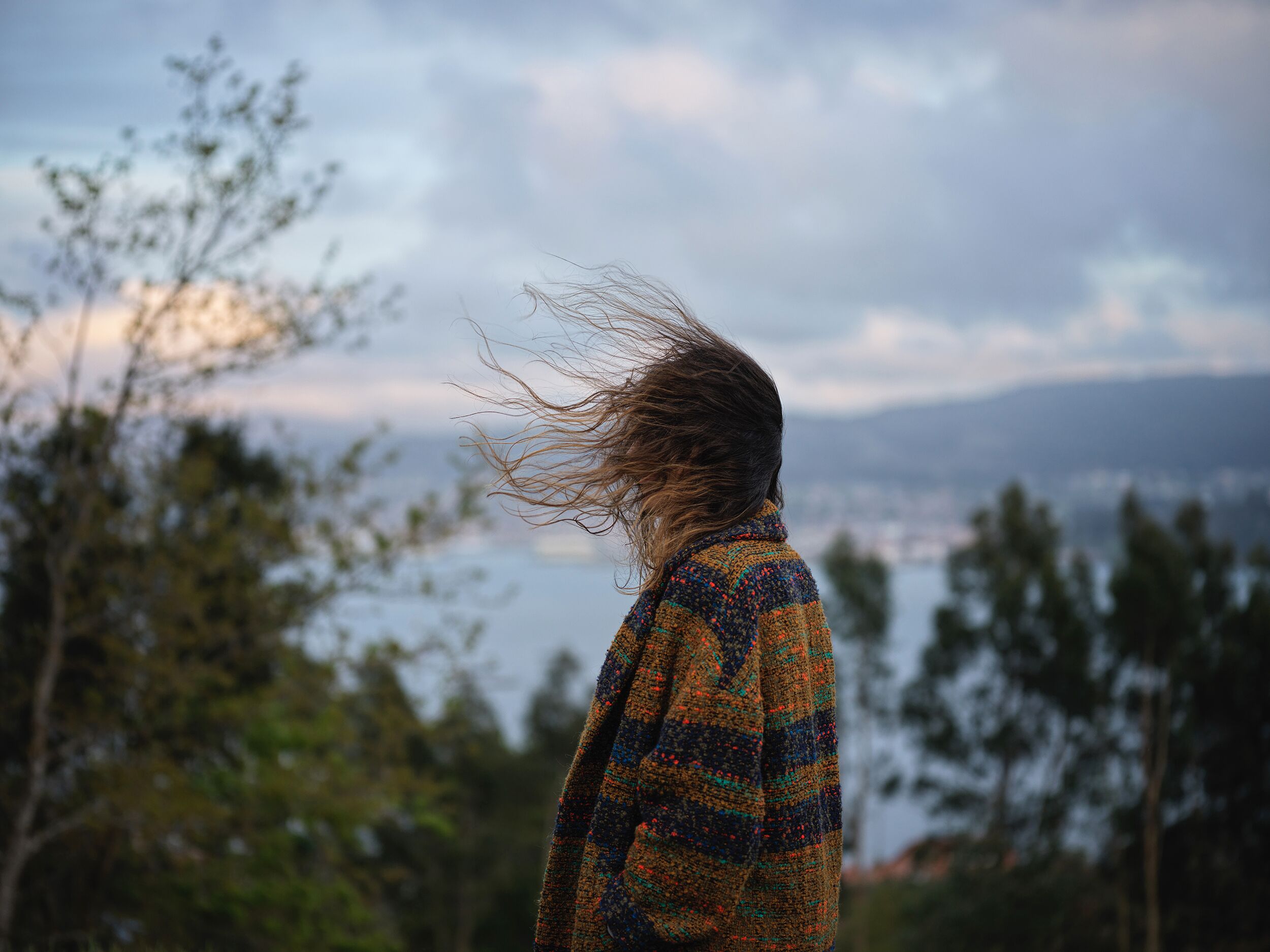 A person standing outdoors with a view of a city in the distance.