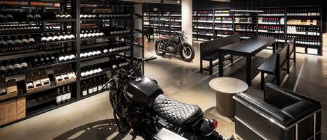 A motorcycle in a showroom with shelves of wine bottles and a seating area.