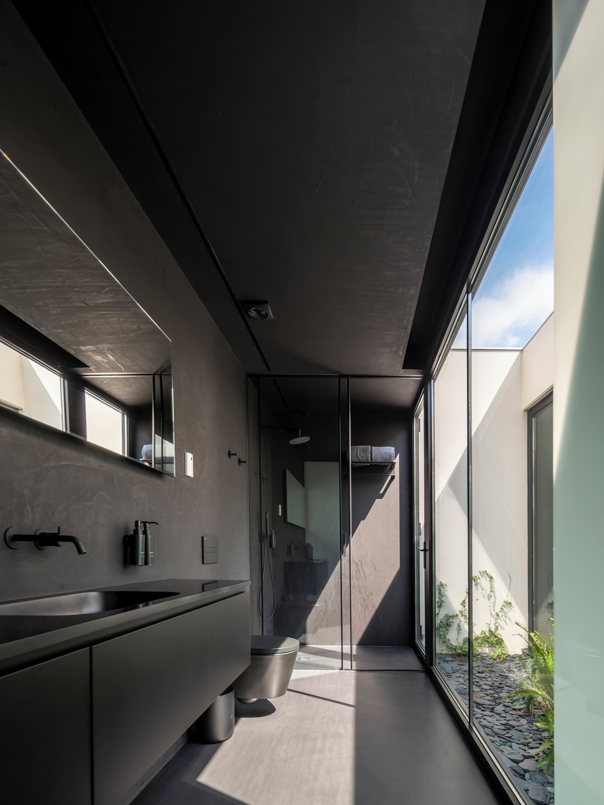 A modern bathroom with a large window, a sink, and a toilet.