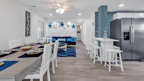 Une cuisine moderne avec un réfrigérateur en acier inoxydable, des tabourets de bar blancs et un mur d’accent bleu.