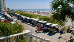 Un parking situé au bord de la plage, avec plusieurs rangées de voiturettes de golf et une plage en arrière-plan.