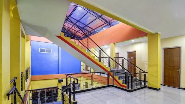 A multi-level interior with a staircase, a skylight, and a wooden door. - OYO 91036 Hotel Simpang Lima Gkpri (Semarang)
