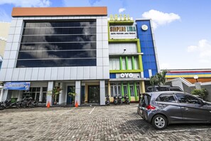 Hotel con fachada moderna, un llamativo letrero que dice "Simpang Lima" y una entrada visible con una cubierta.