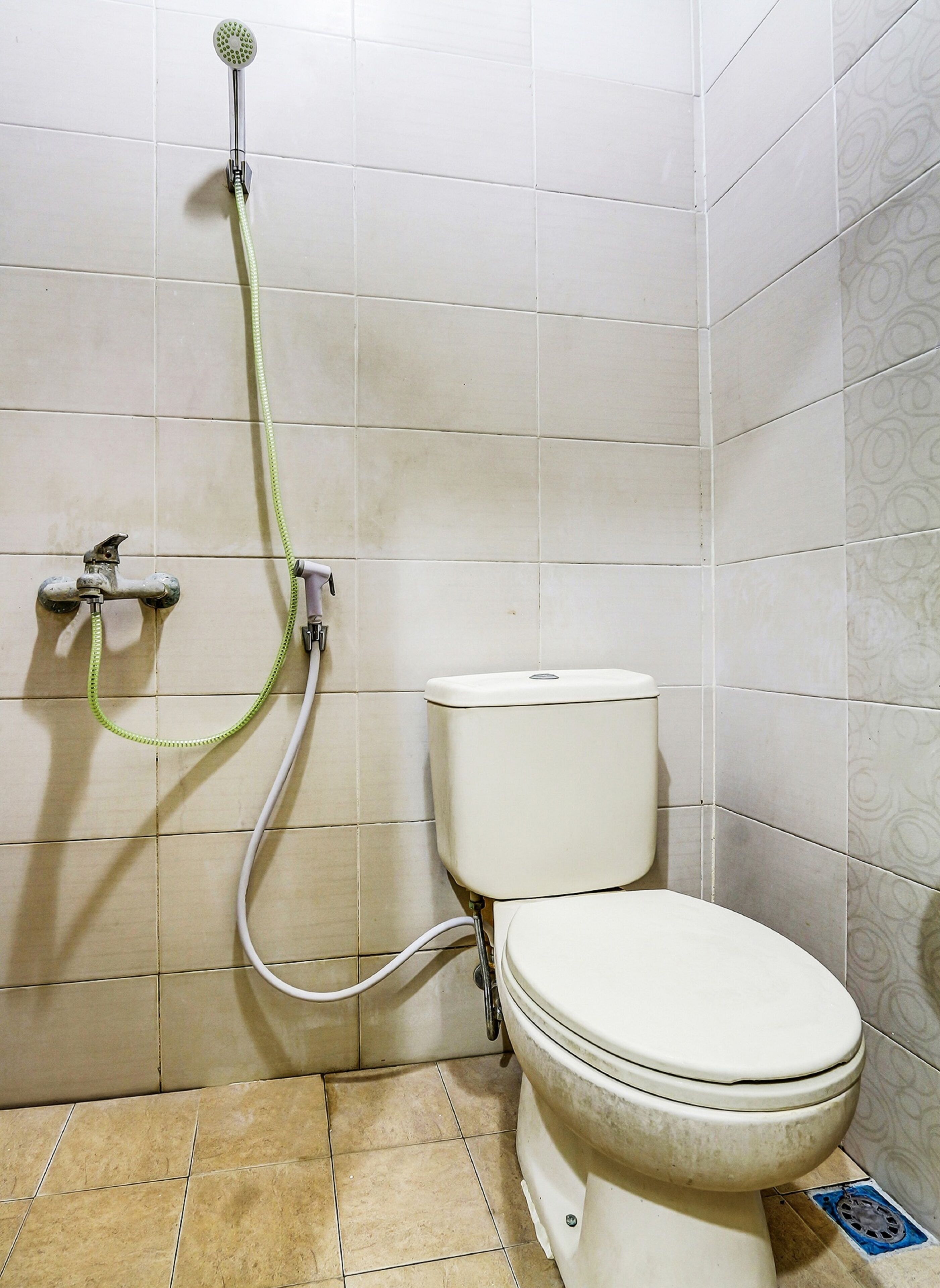 A bathroom with a toilet, a shower, and a wall-mounted faucet.