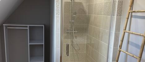 Une salle de douche moderne avec une paroi de verre, une échelle en bois et une étagère blanche.