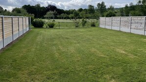 A fenced outdoor area with a grassy field, trees, and a cloudy sky. - Gîte near Le Treport and Criel sur Mer (Saint-Martin-le-Gaillard)