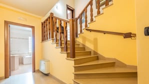 Un escalier avec des rampes en bois et des marches de couleur beige menant à l’étage supérieur.