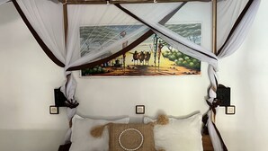 Un letto a baldacchino, un quadro al muro e un cuscino decorativo.