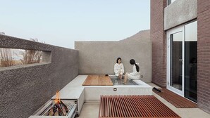 A modern outdoor relaxation area with a fire pit, seating, and a view of the surrounding landscape. - IJE Namhae (Namhae)