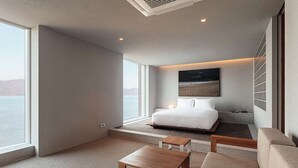 A modern bedroom with a large bed, a small table, a sofa, and a painting on the wall. - IJE Namhae (Namhae)