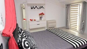 Camera da letto con un letto, una cassettiera, uno specchio, un termosifone e una finestra con persiane.
