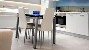 Una cucina moderna con mobili bianchi, un'area pranzo con tavolo e sedie, e un lucernario.