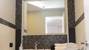 Un baño con lavamanos blanco, un espejo y un perchero para toallas.