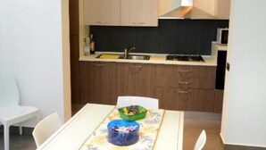 Una cocina moderna con armarios blancos, horno empotrado y lámpara de techo verde.