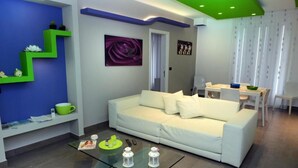 Una sala de estar moderna con un sofá blanco, una mesa de centro de vidrio y una pared de acento verde.