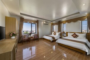 Quarto de hotel com duas camas, televisão, secretária e uma cadeira.