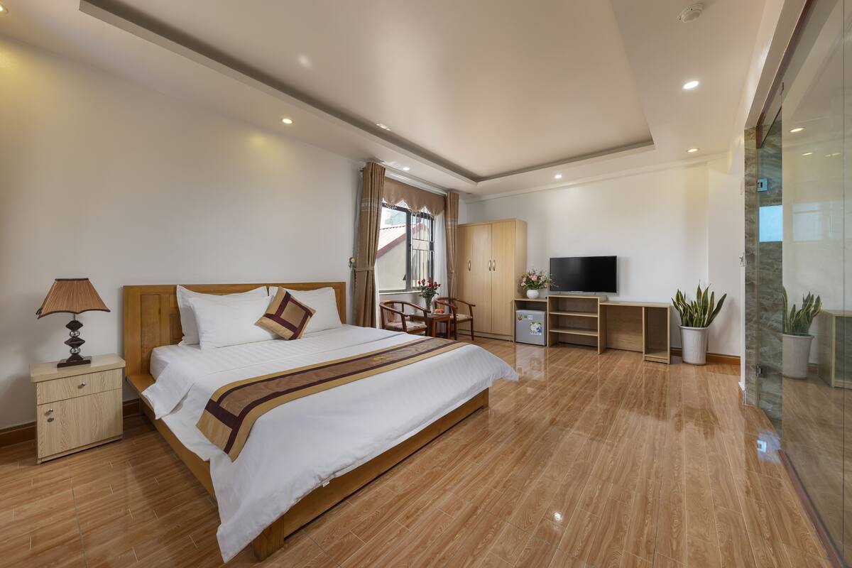 Ein modernes Hotelzimmer mit einem großen Bett, einem Schreibtisch, einem Fernseher und Topfpflanzen.