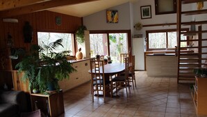 Una cocina acogedora con armarios de madera, una mesa de comedor con sillas y ventanas amplias que ofrecen vistas al exterior.