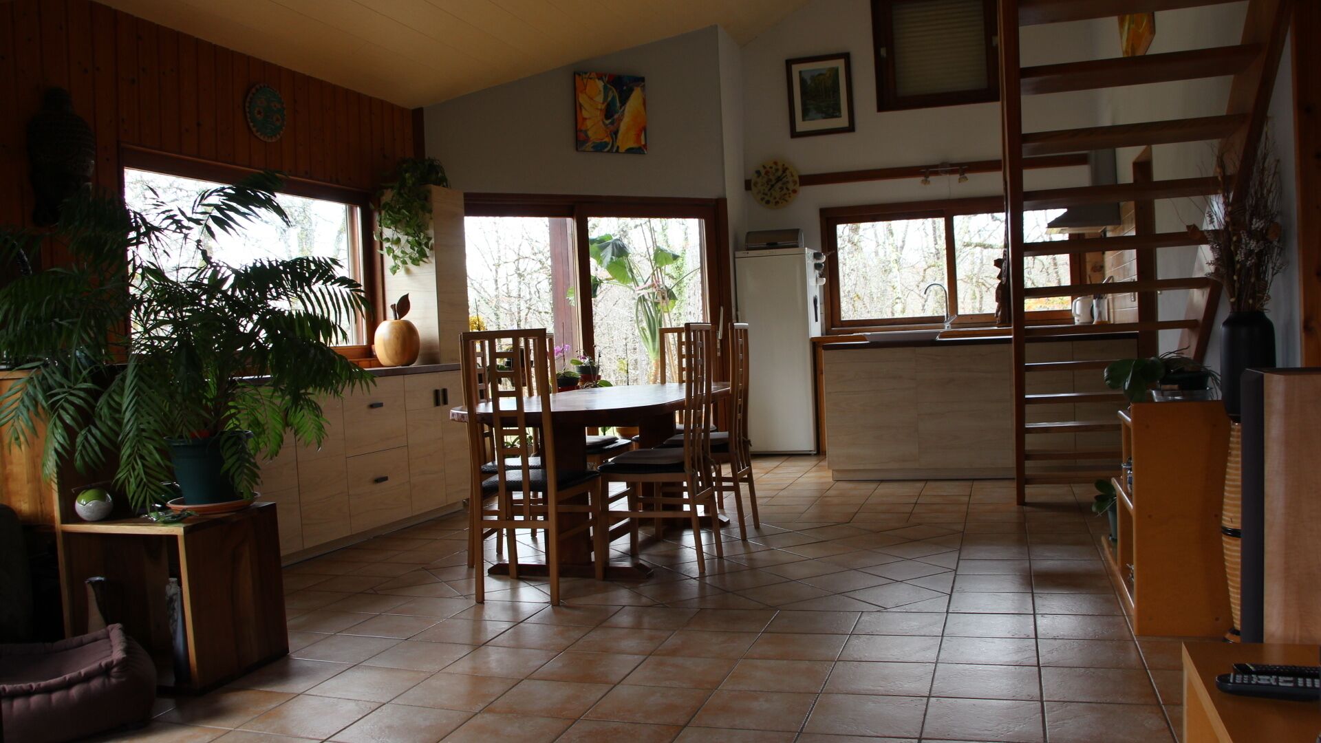 A spacious kitchen with a dining area, wooden cabinets, and large windows.
