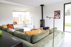 A modern living room with a green sofa, a glass coffee table, and a black fireplace.