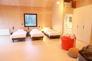 A bedroom with three beds, a large window, a shower, and a wardrobe.