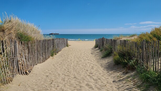 A sandy path leading to a beach with wooden fences on either side. - Holiday home near the beach (Cap d'Agde)
