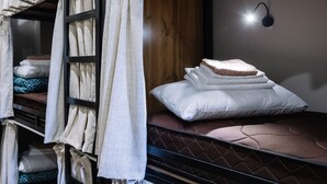 En køjeseng med madras, puder og gavl.