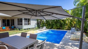 A backyard with a swimming pool, outdoor furniture, and a covered patio area. - La Belle aimante, beautiful home with pool (HORSESHOE BAY)