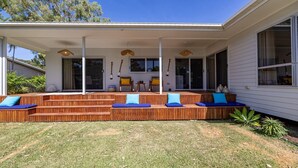 A covered outdoor seating area with wooden steps and blue cushions, a small table, and chairs. - La Belle aimante, beautiful home with pool (HORSESHOE BAY)